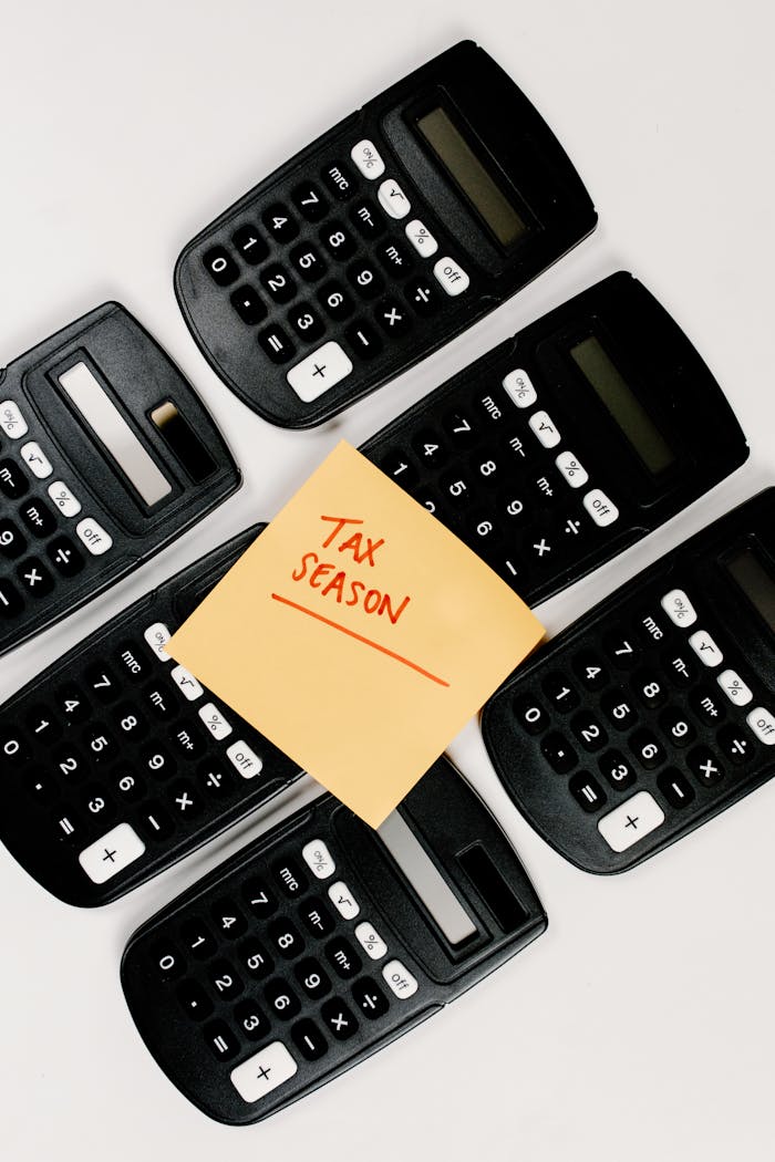 Top view of black calculators arranged around Tax Season sticky note, perfect for finance concepts.